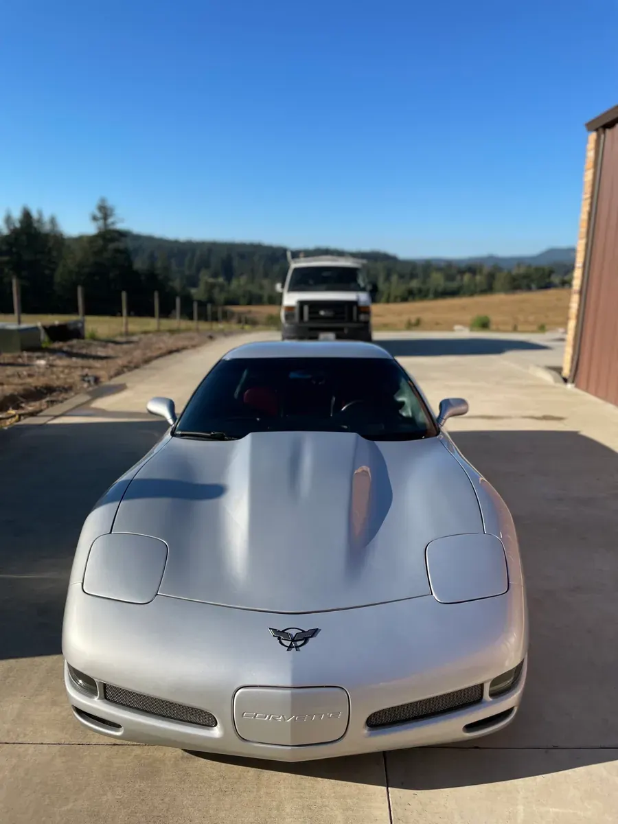 The Tan's Auto Detailing work van behind a freshly detailed silver Corvette on a customer's driveway