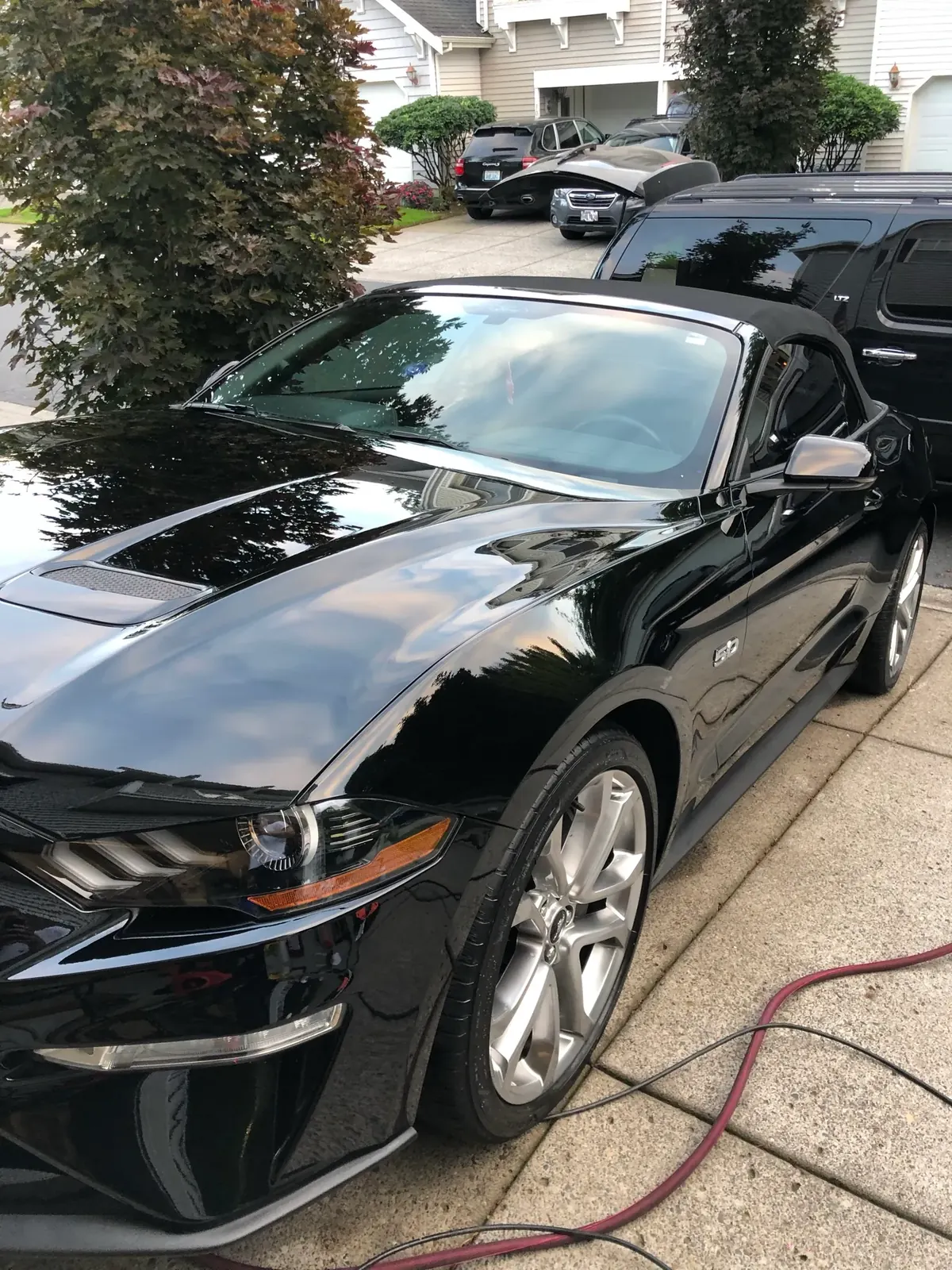 Black Ford Mustang GT convertible detailed at the curb outside a customer's home